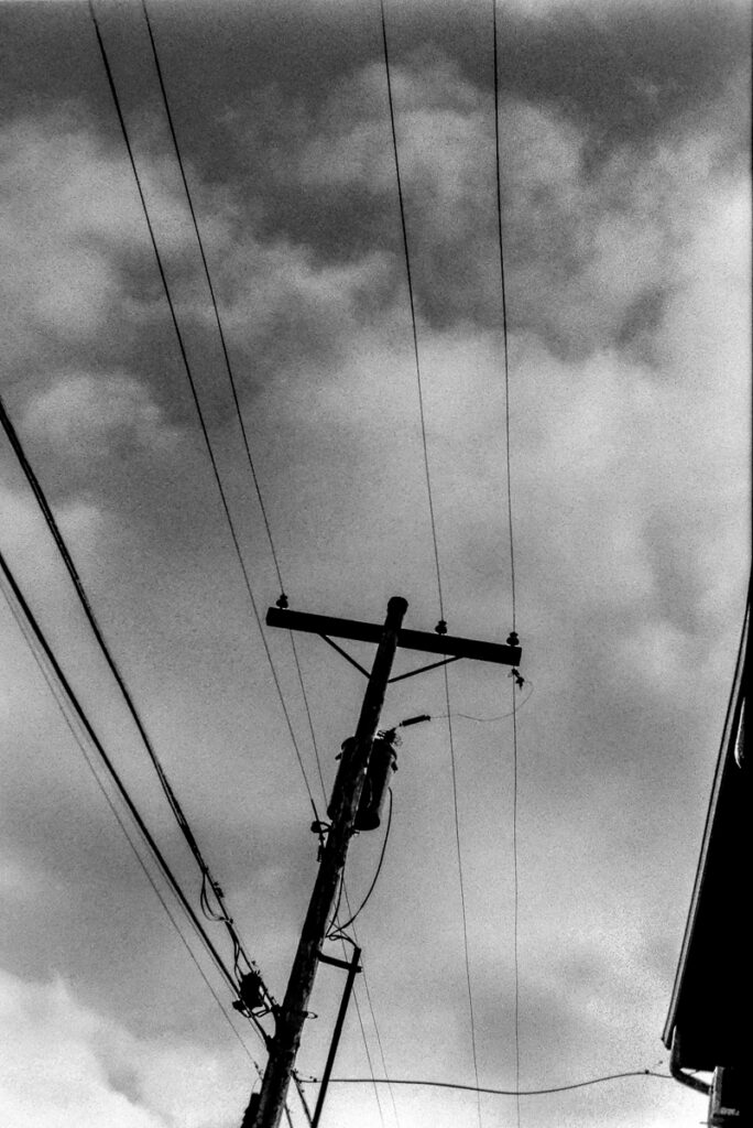 Black and white image of a telegraph pole against dramatic clouds