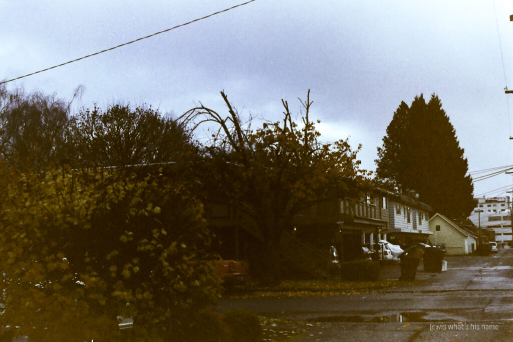 Photo of a street where it meets an alley.  The colours are washed out and faded, giving it the look of a photograph that's faded with time.