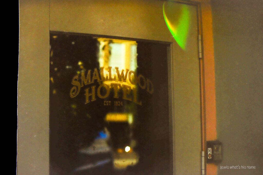 Photo of a door, with the words 'smallwood hotel' written on it.  There's green artifacts on the photo.  The left edge has been cut short, leaving a black bar down the side.